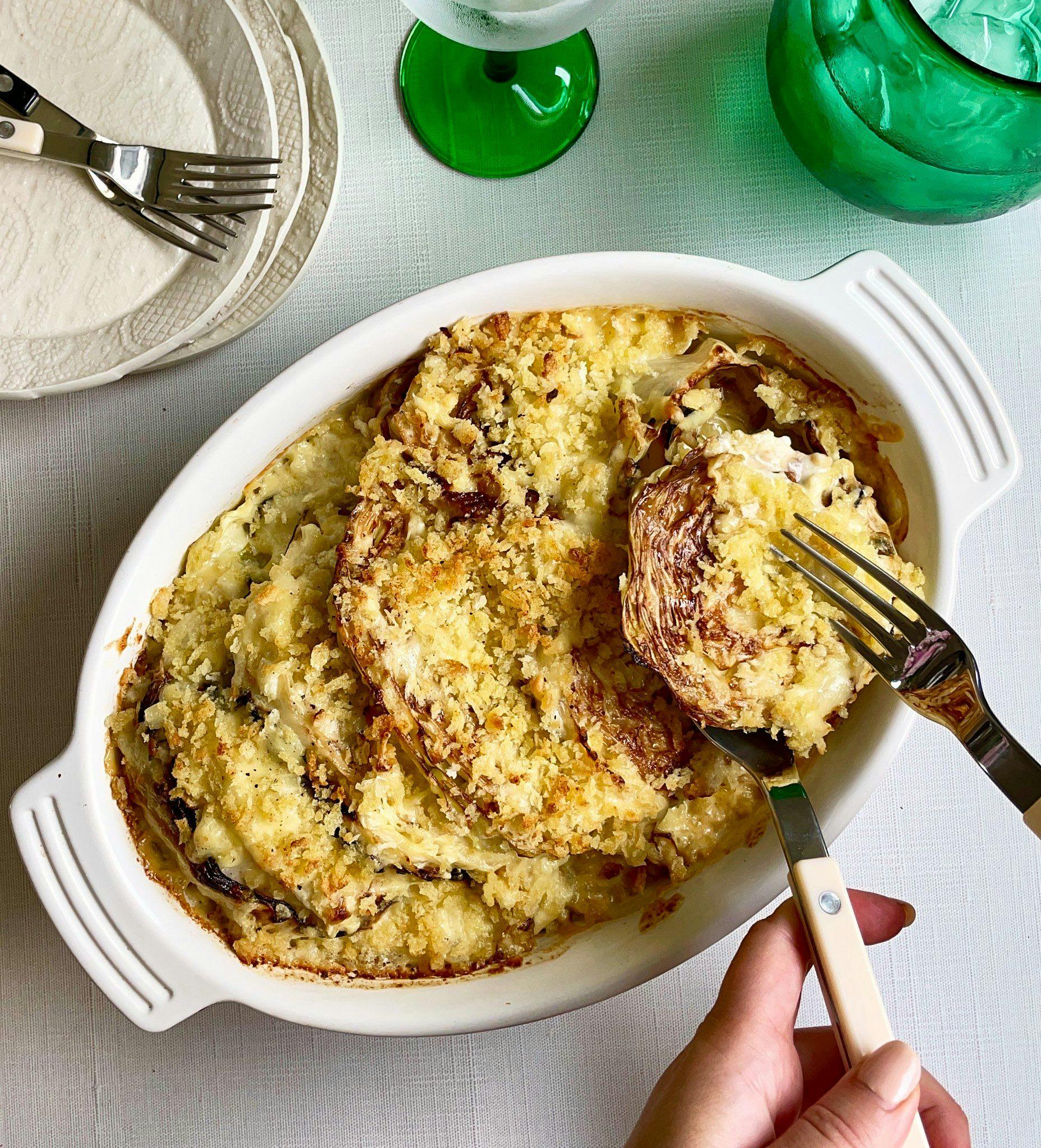 Charred cabbage gratin in a serving dish with serving utensils