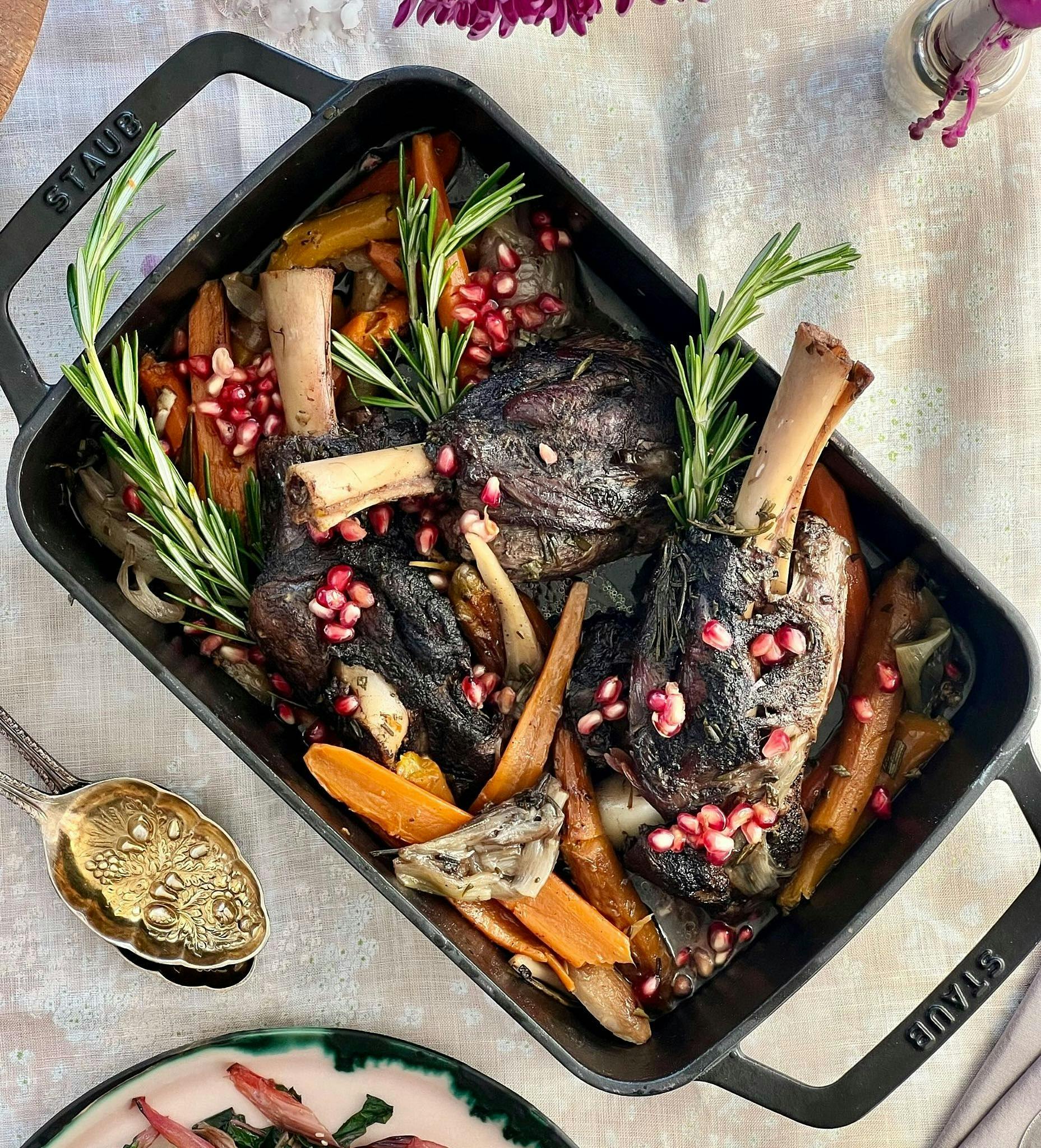 Braised Lamb with carrots, pomegranate seeds, & rosemary sprigs in serving dish