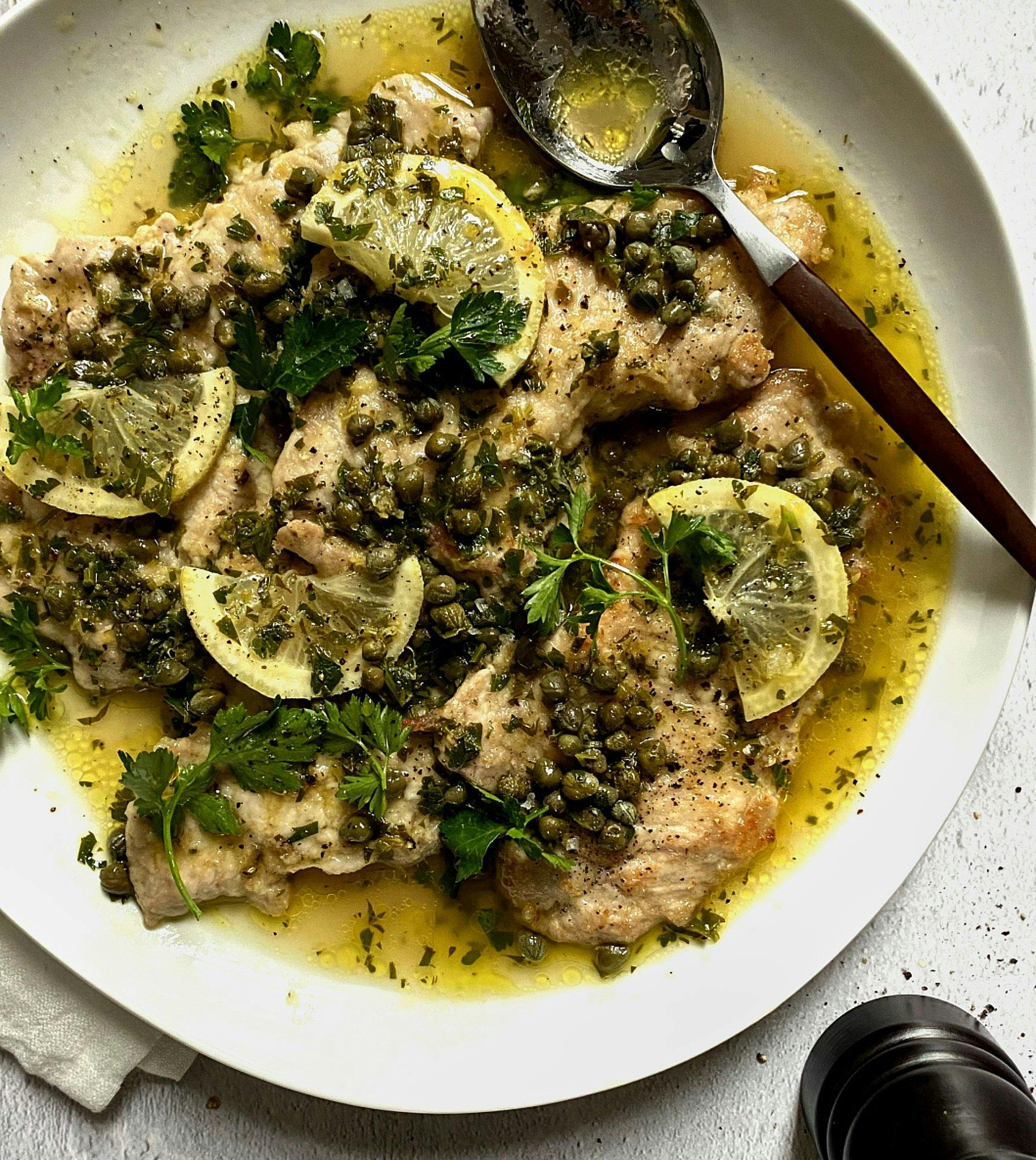 veal piccata on serving plate with spoon